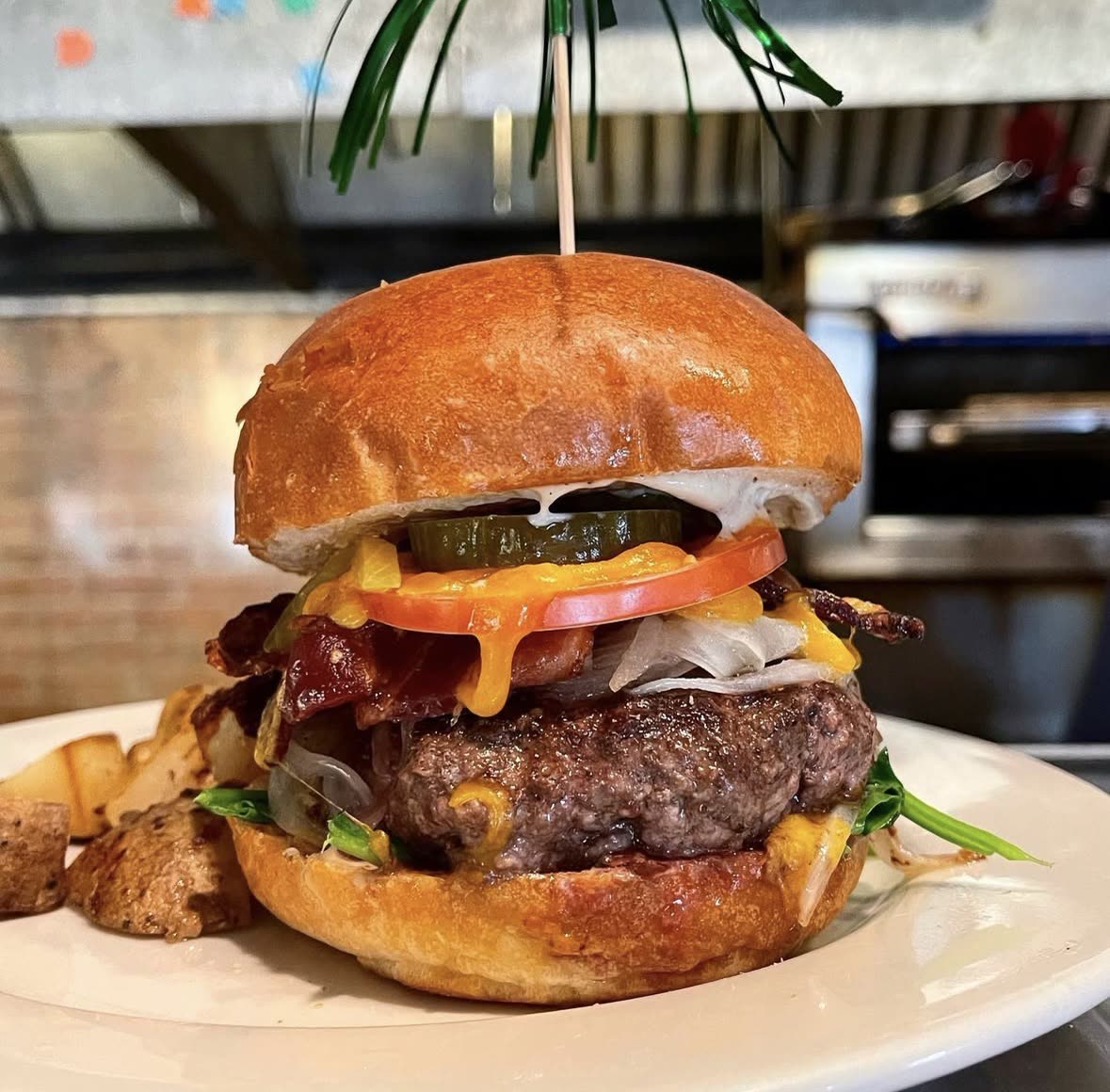Bacon cheeseburger with tomato, pickle and grilled onions, with home fries